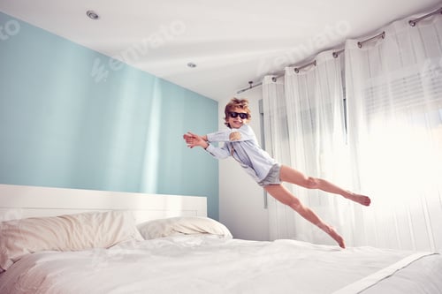 Preview: Joyful boy jumping on bed in morning