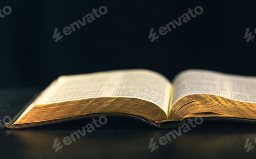 Preview: Open Bible on a black background. Religion concept.