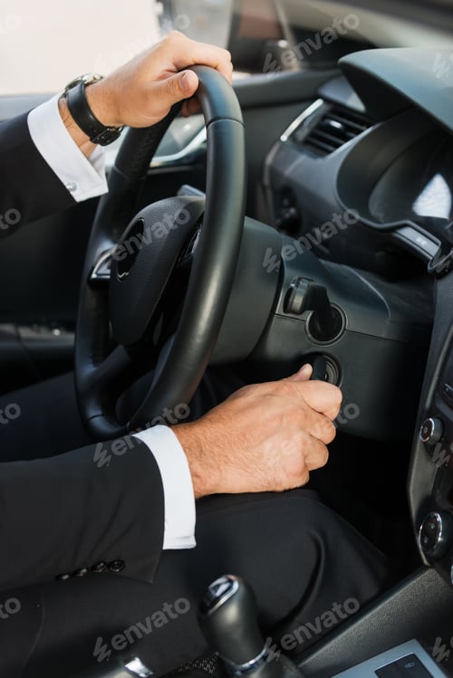 Preview: Man starting a car. Close-up of man in formalwear starting a car