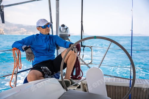 Preview: Young man captain stands at the helm and controls a sailboat during a journey by sea
