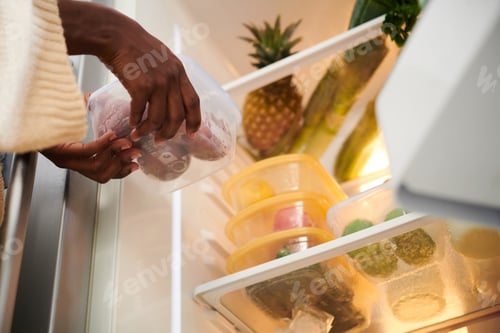 Preview: Woman Putting Container in Refrigerator