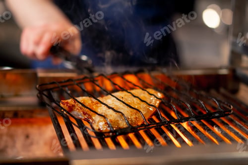 Vista previa: close up in a Japanese restaurant chef in a blue uniform fries fish on the grill in the kitchen