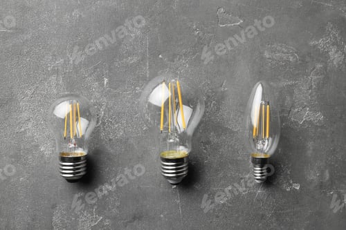 Preview: New vintage lamp bulbs on grey stone surface, flat lay