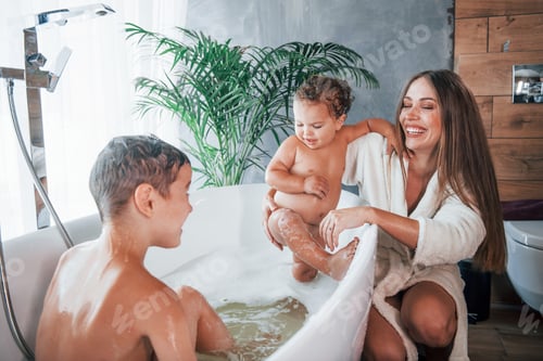 Preview: After washing. Young mother helps her son and daughter