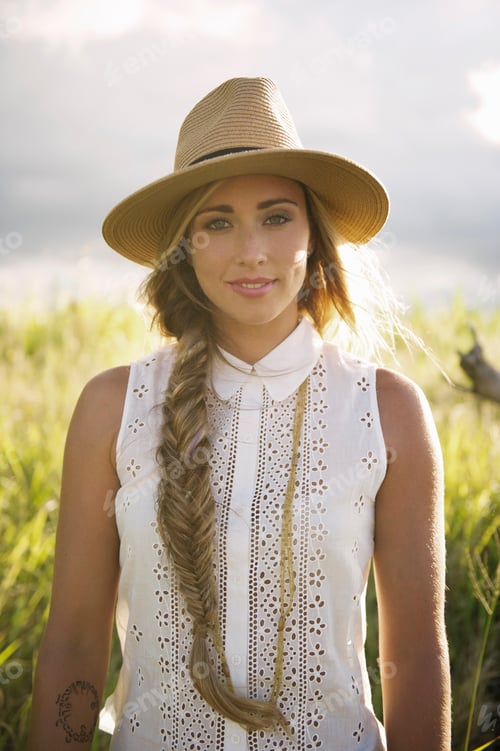 Preview: A serene woman in a field at sunset wearing a straw hat