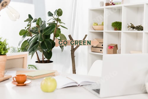 Preview: workspace with apple and laptop near go green sign in modern office, environmental saving concept