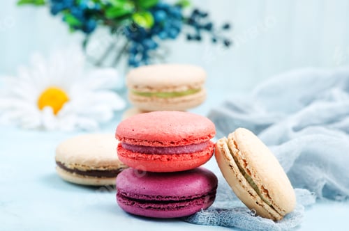 Colorful Macarons Stacked with Flowers on Blue Surface