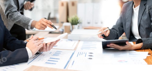 Preview: Professional team analyzing financial data on charts, tablets, and calculators during a meeting.