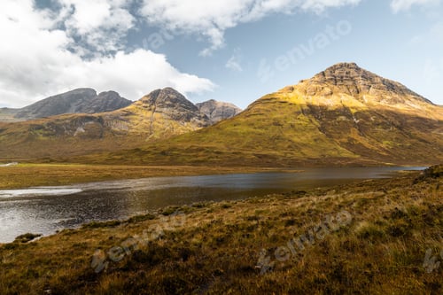 Preview: Lush, green grassy area with a narrow river flowing between the mountains on a sunny day