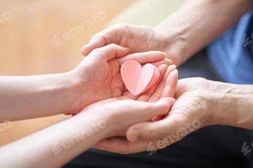 Preview: Hands of caregivers and elderly people with heart-shaped objects