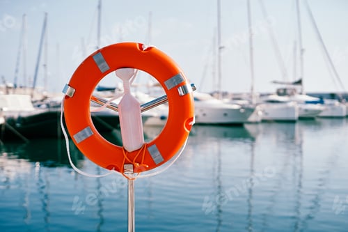 Preview: Red lifebuoy on a metal stand with white plastic fastener by the sea