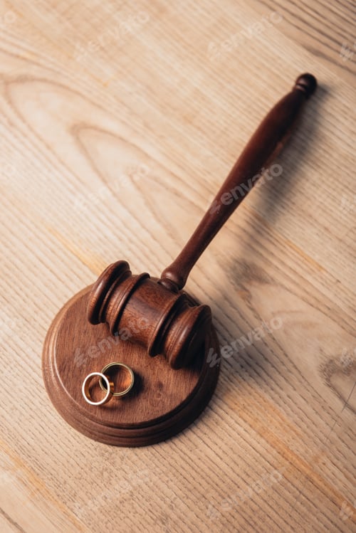 Preview: top view of golden rings on wooden gavel, divorce concept