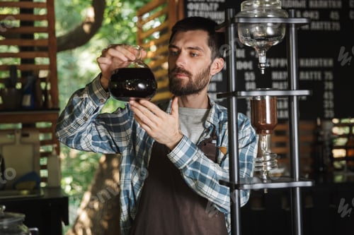 Preview: Image of satisfied barista boy making coffee while working in ca