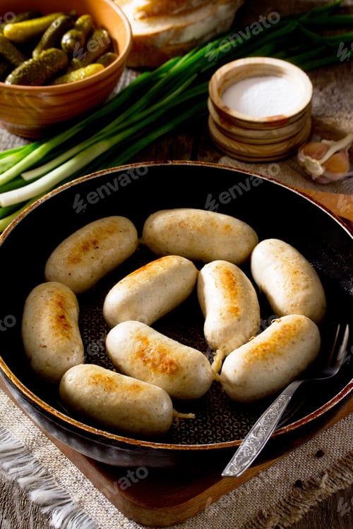 Preview: Homemade baked grilled meat chicken sausage in a cast iron pan on a rustic background.