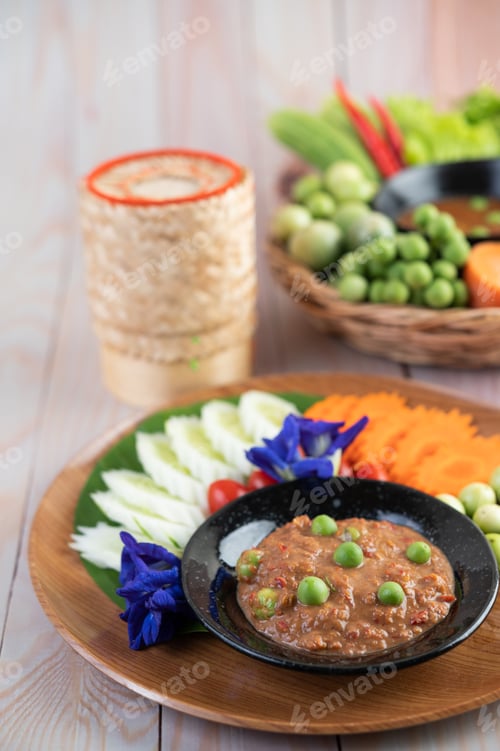 Preview: Chili paste paste in a bowl with eggplant, carrots, chili, cucumbers in a basket on wood table