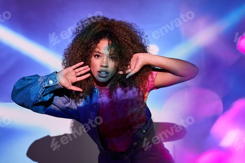 Preview: Stylish black woman touching hair in neon lights