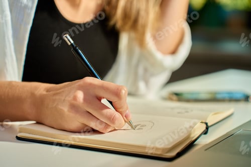 Preview: Illustrator drawing sketches in notebook at home office desk