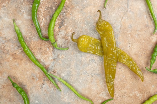 Preview: Pickled and fresh green peppers on marble surface