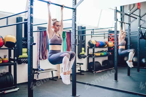 Preview: Athletic woman hanging on horizontal bar training abs