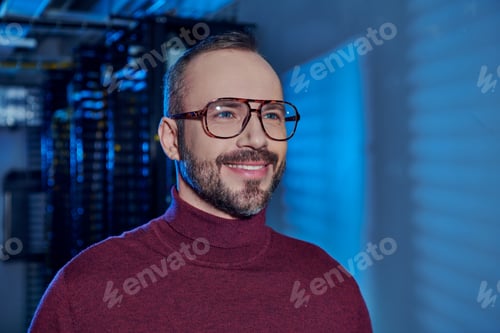 Preview: cheerful good looking specialist in turtleneck with glasses smiling and looking away, data center