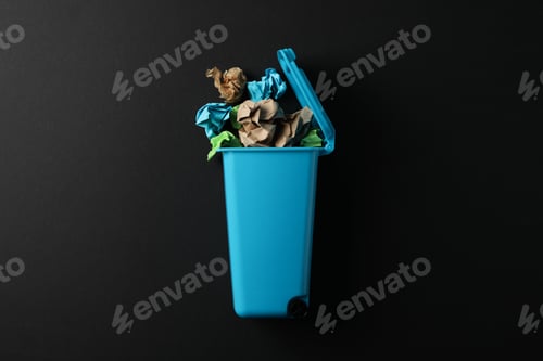 Preview: Recycle bin with trash on black background, space for text
