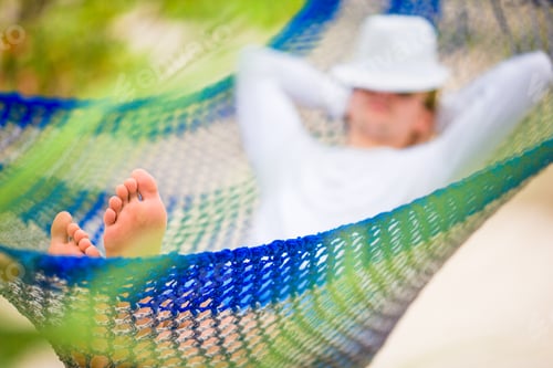 Preview: Lazy time. Man in hat in a hammock on a summer day