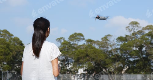 Preview: Woman control fly drone with blue sky at outdoor