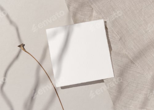 Preview: Blank paper card on natural beige stone and linen cloth with hard shadows, top view, boho mockup