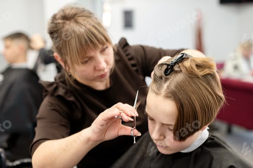 Preview: Professional hairstylist carefully cutting a young client's hair in a modern salon setting