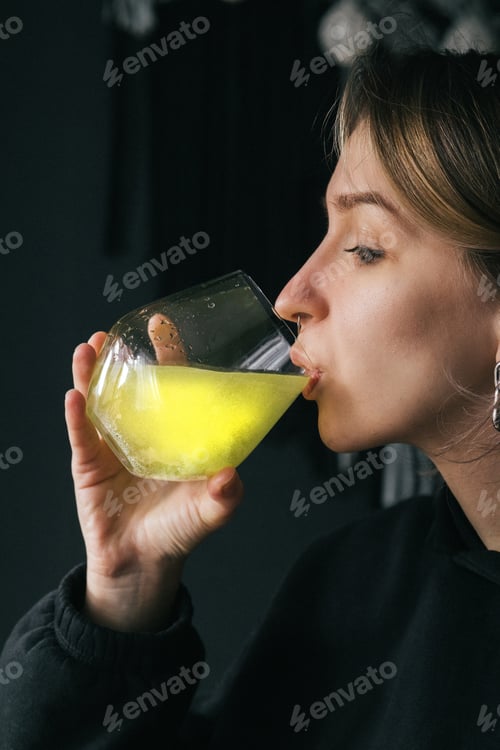 Preview: a girl dilutes effervescent vitamins in a glass of water and drinks them - maintenance self-care.