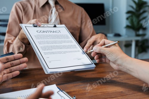 Preview: Businessman showing contract details to client using pen in office meeting