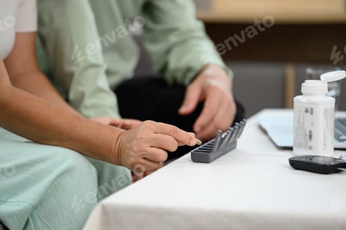 Preview: Elderly people taking pills from pillbox and vitamins for daily medication.