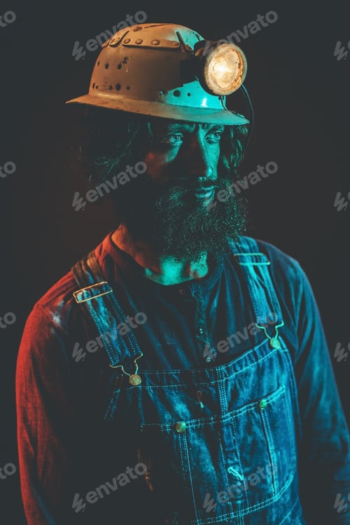 Preview: Close Up Of Male Miner Wearing Lit Safety Helmet Lamp And Overalls Staring To The Side And