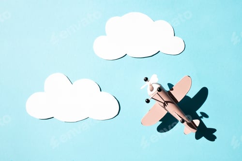 Preview: Toy retro airplane and paper clouds on a blue background.