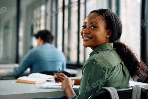Preview: Happy black female student attending a lecture at the university and looking at camera.