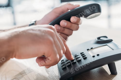 Preview: cropped shot of man making dialing stationary phone to make call