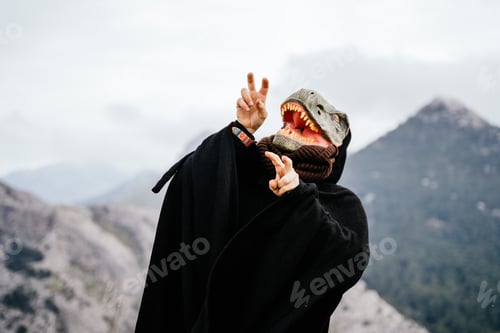 Preview: Caucasian man wearing an angry dinosaur mask and a cape in the Sierra de Tramuntana mountain range