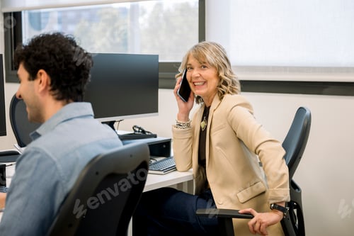 Preview: Mature businesswoman smiling and talking on cell phone
