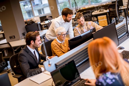 Preview: Senior businesswoman working together with young business people in modern office
