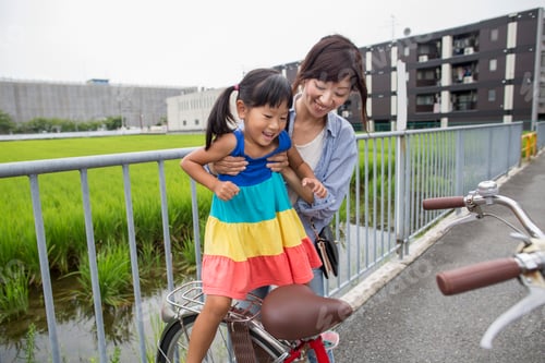 Preview: A mother lifting her daughter onto a bicycle.