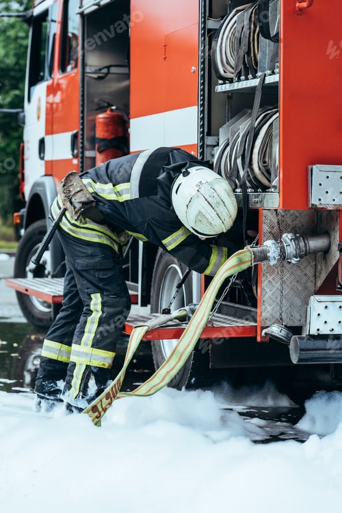 Preview: partial view of firefighter in protective uniform checking water hose on street