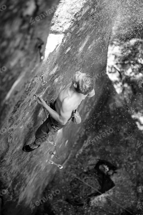 Preview: Muscular rock climber climbs on cliff wall with rope