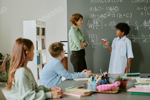 Preview: Teenage Black Boy Explaining Math Problem to Caucasian Female Teacher in Classroom