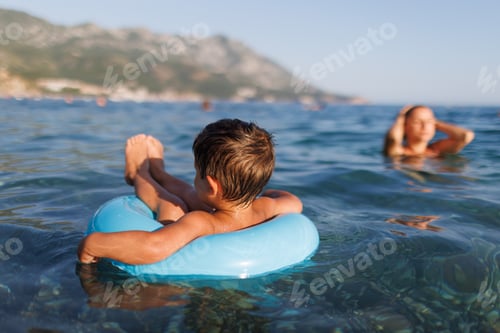 Preview: A little boy swims with an inflatable ring in the sea