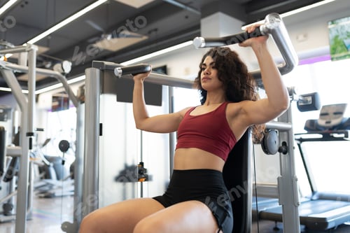 Preview: Latin woman exercising with a shoulder press machine