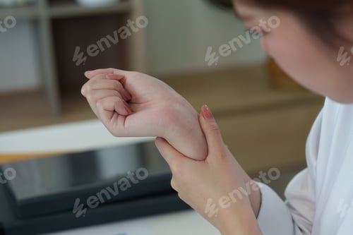 Preview: Mental Health Awareness. Young woman checking pulse at desk, reflecting on stress and wellness.