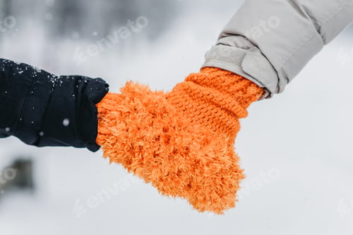 Preview: The pair hold hands in orange mittens