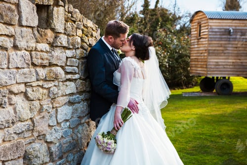 Preview: A bride and groom kissing on their wedding day standing in a garden.