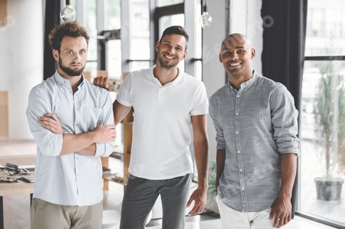 Preview: multiethnic young businessmen looking at camera while standing in office