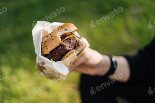 Preview: Girl enjoying takeaway burger in park